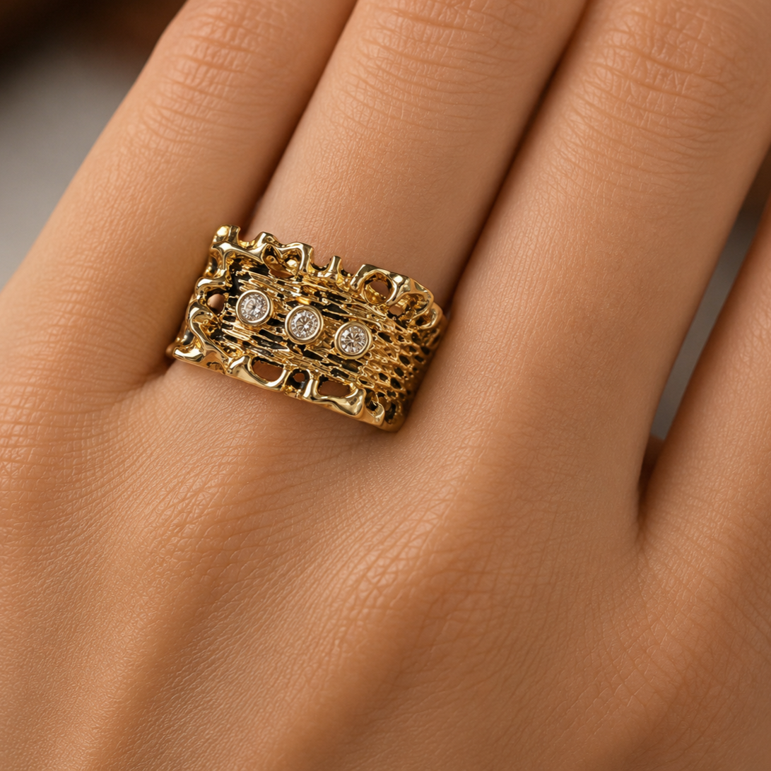 “Hand wearing a bold 14K yellow gold antiqued diamond ring featuring a richly textured design with three bezel set round diamonds and substantial vintage-inspired styling