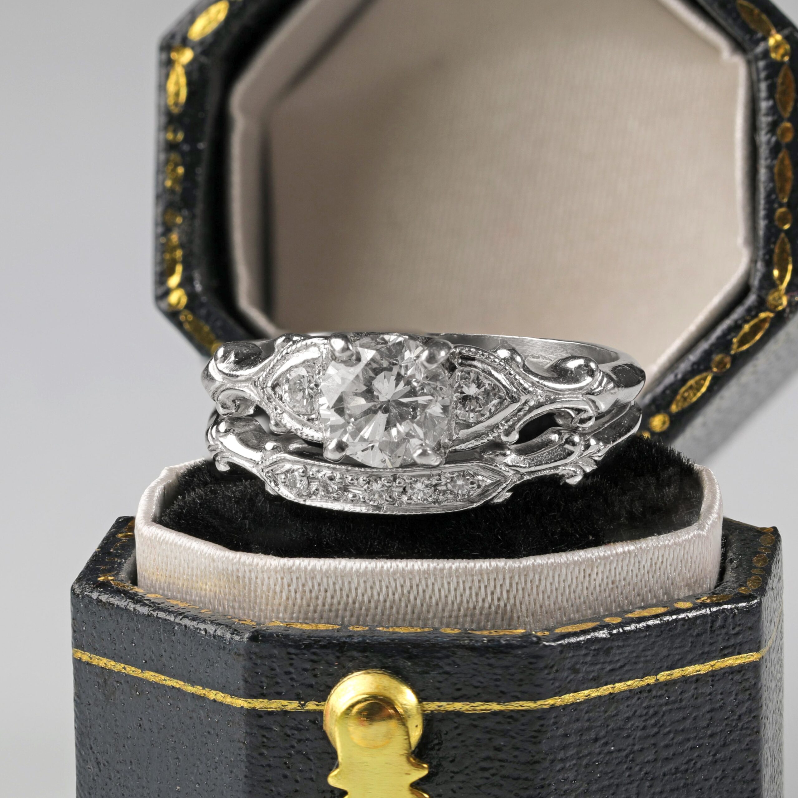 Platinum diamond wedding set displayed sitting on a ring box featuring a 0.62 carat round brilliant center diamond with sparkling accent diamonds along the engagement ring and matching band.