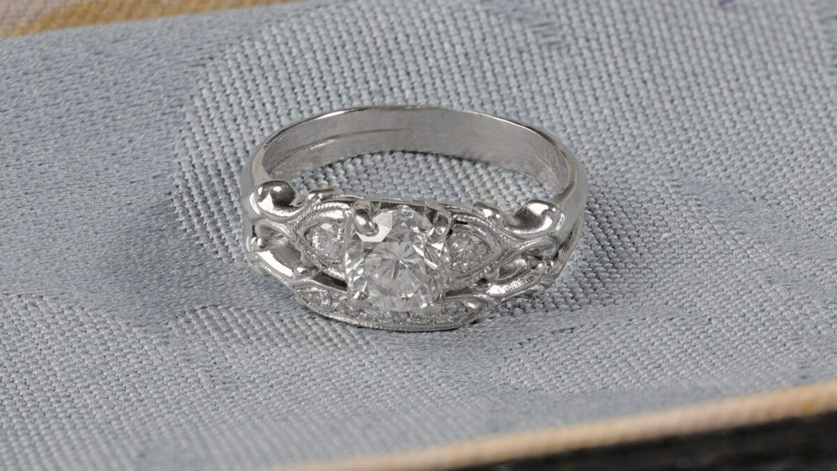 Platinum diamond wedding set displayed on a blue background featuring a 0.62 carat round brilliant center diamond with sparkling accent diamonds along the engagement ring and matching band.