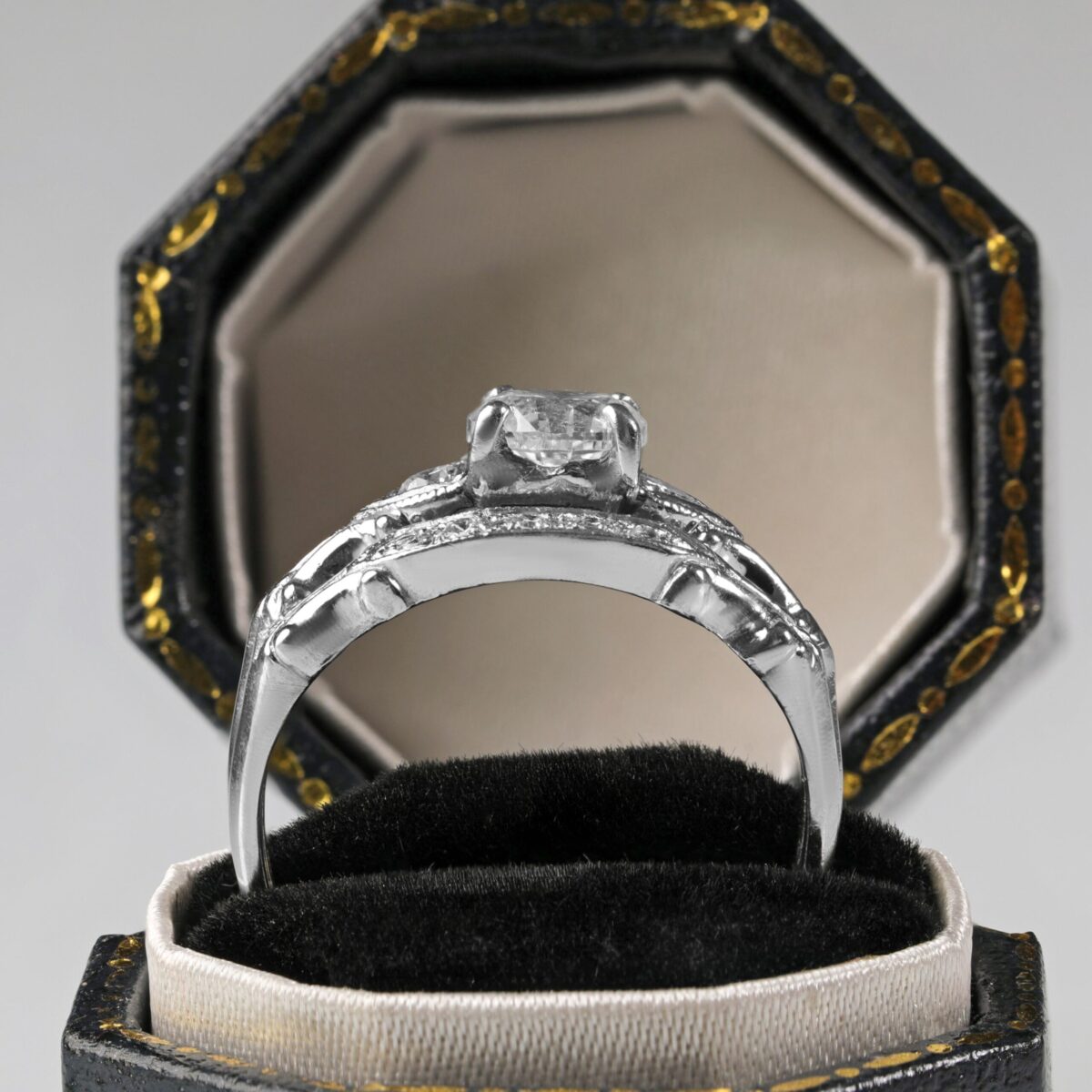 Platinum diamond wedding set displayed in a ring box featuring a 0.62 carat round brilliant center diamond with sparkling accent diamonds along the engagement ring and matching band. View is from the side