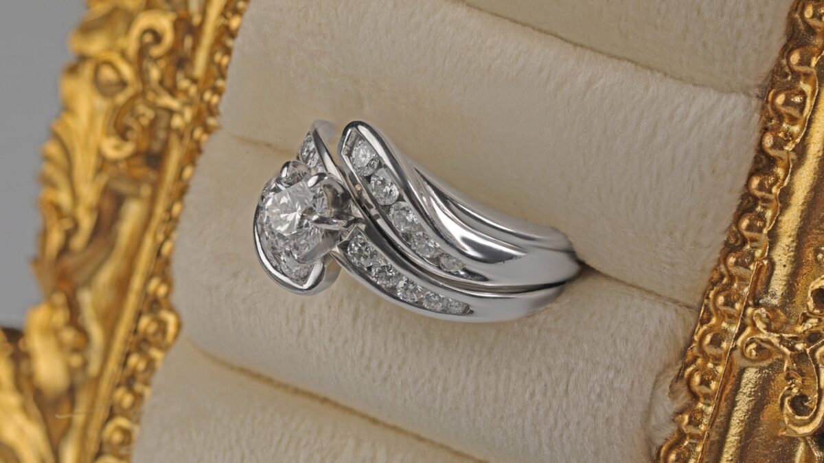 Custom 14K white gold diamond wedding ring from a side angle displayed in a jewelry frame featuring a brilliant center diamond with channel set accent diamonds, custom made in Northern California