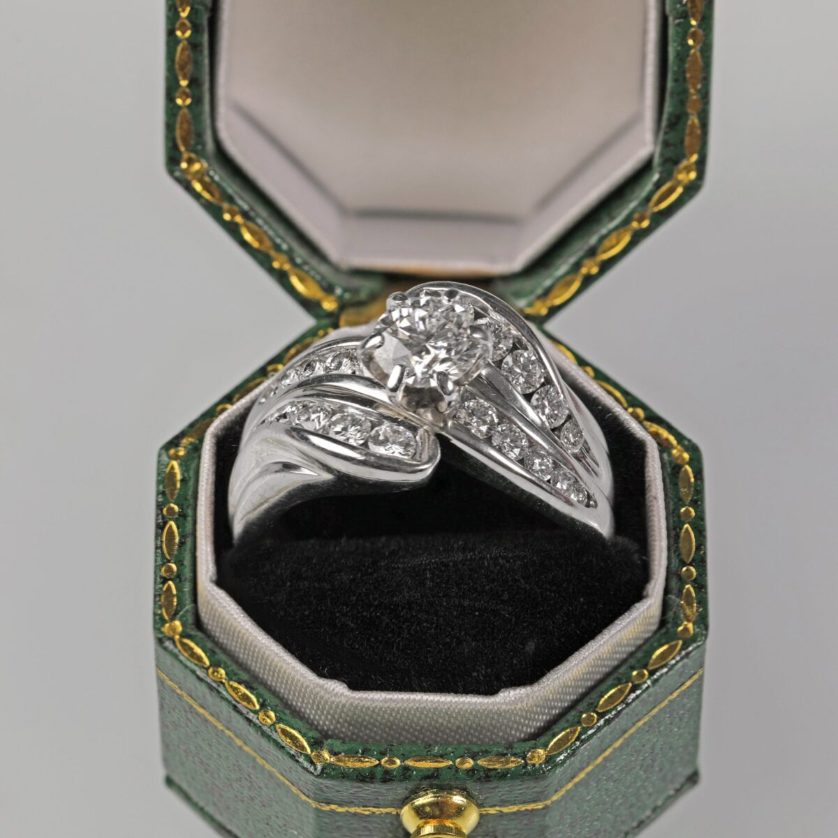 Custom 14K white gold diamond wedding ring set from a side view displayed in a green ring box featuring a brilliant center diamond with channel set accent diamonds, custom made in Northern California
