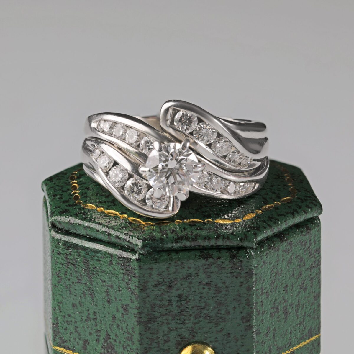 Custom 14K white gold diamond wedding ring set sitting on top of a green ring box featuring a brilliant center diamond with channel set accent diamonds, custom made in Northern California