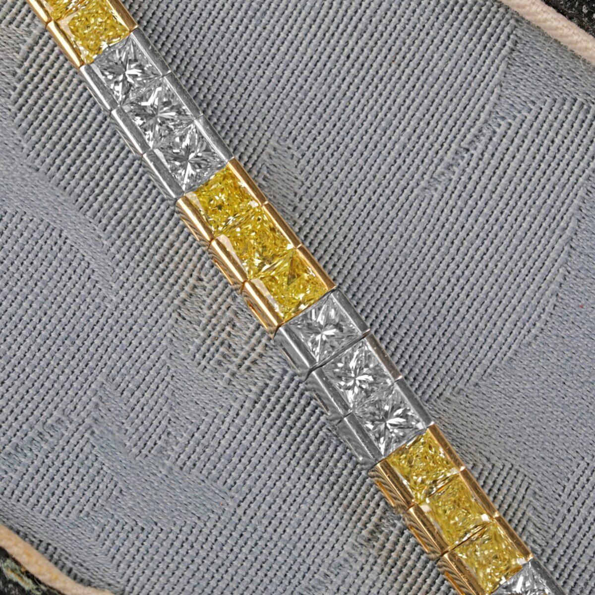 Yellow and white diamond tennis bracelet featuring alternating fancy yellow and white diamonds in an elegant tapered design crafted in 18K yellow gold and platinum.