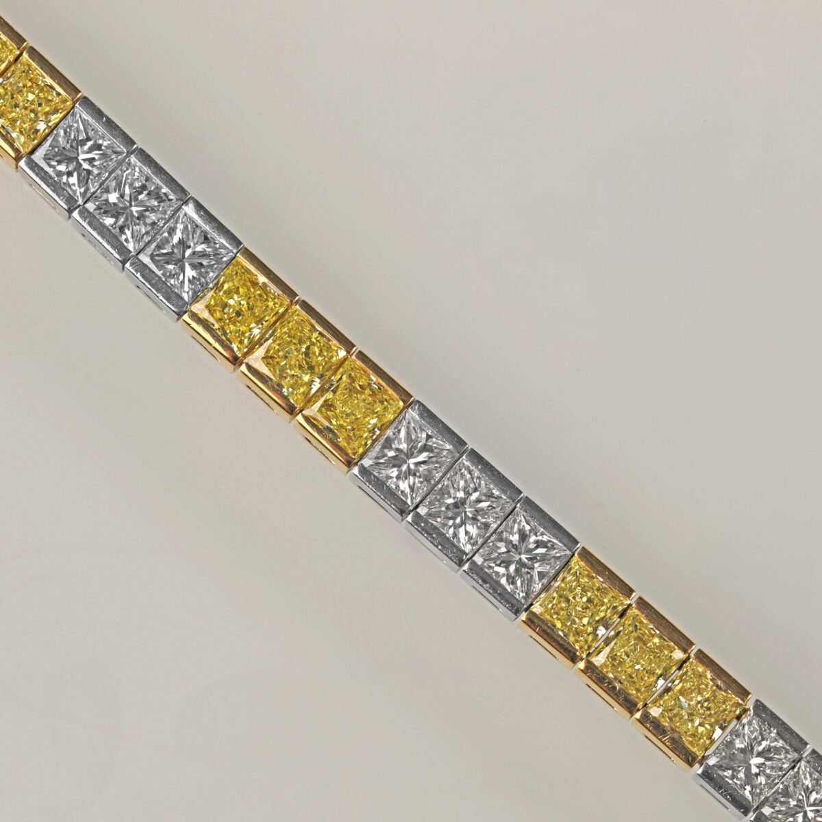 Yellow and white diamond tennis bracelet featuring alternating fancy yellow and white diamonds in an elegant tapered design crafted in 18K yellow gold and platinum.