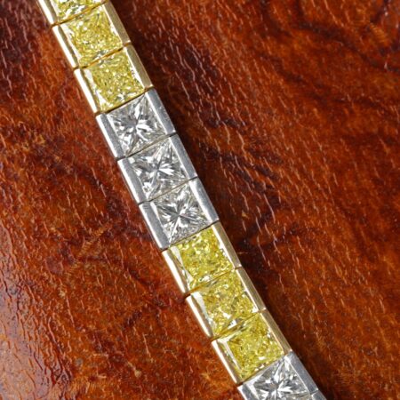 Yellow and white diamond tennis bracelet featuring alternating fancy yellow and white diamonds in an elegant tapered design crafted in 18K yellow gold and platinum